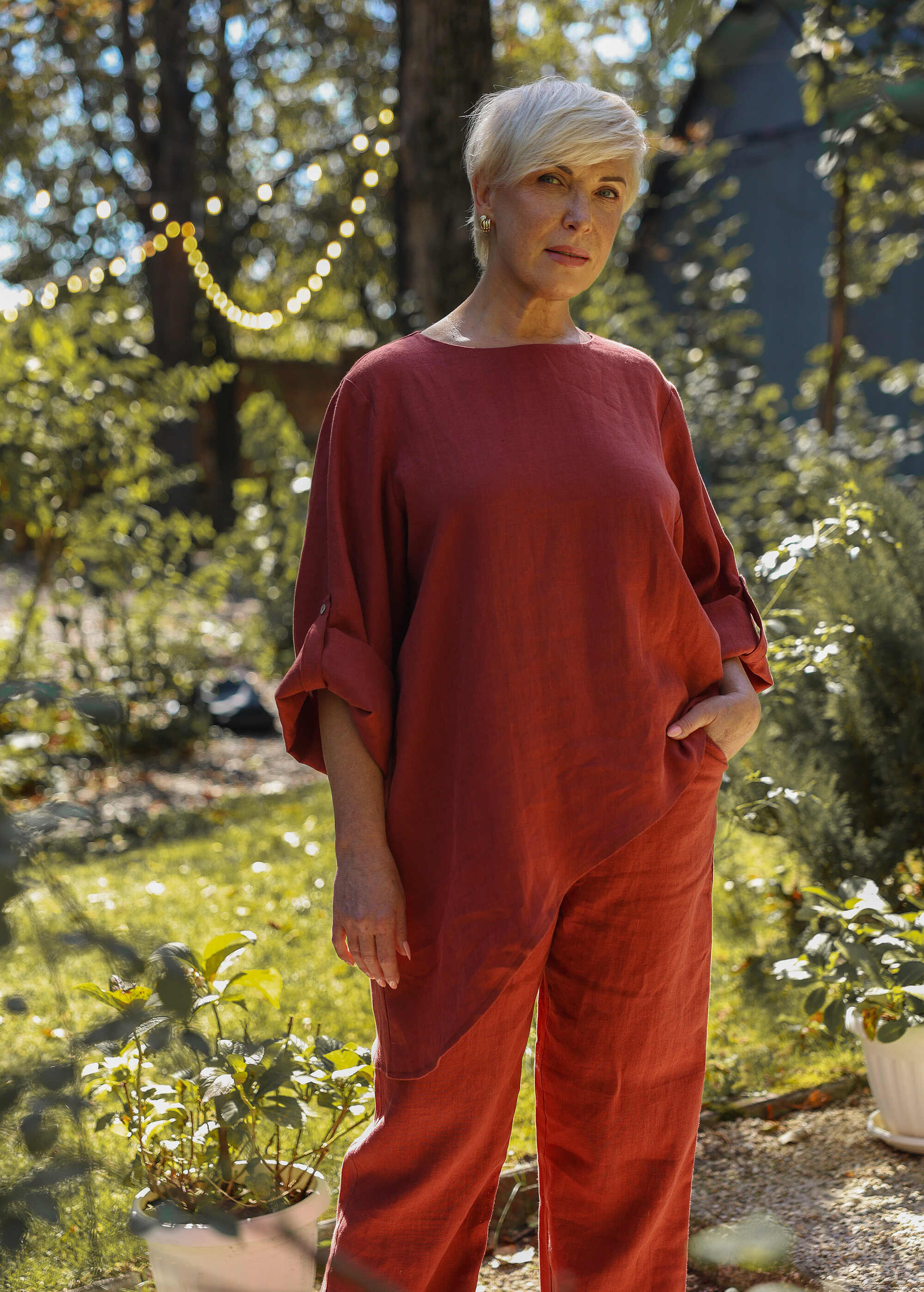 a woman in a red jumpsuit standing in a garden