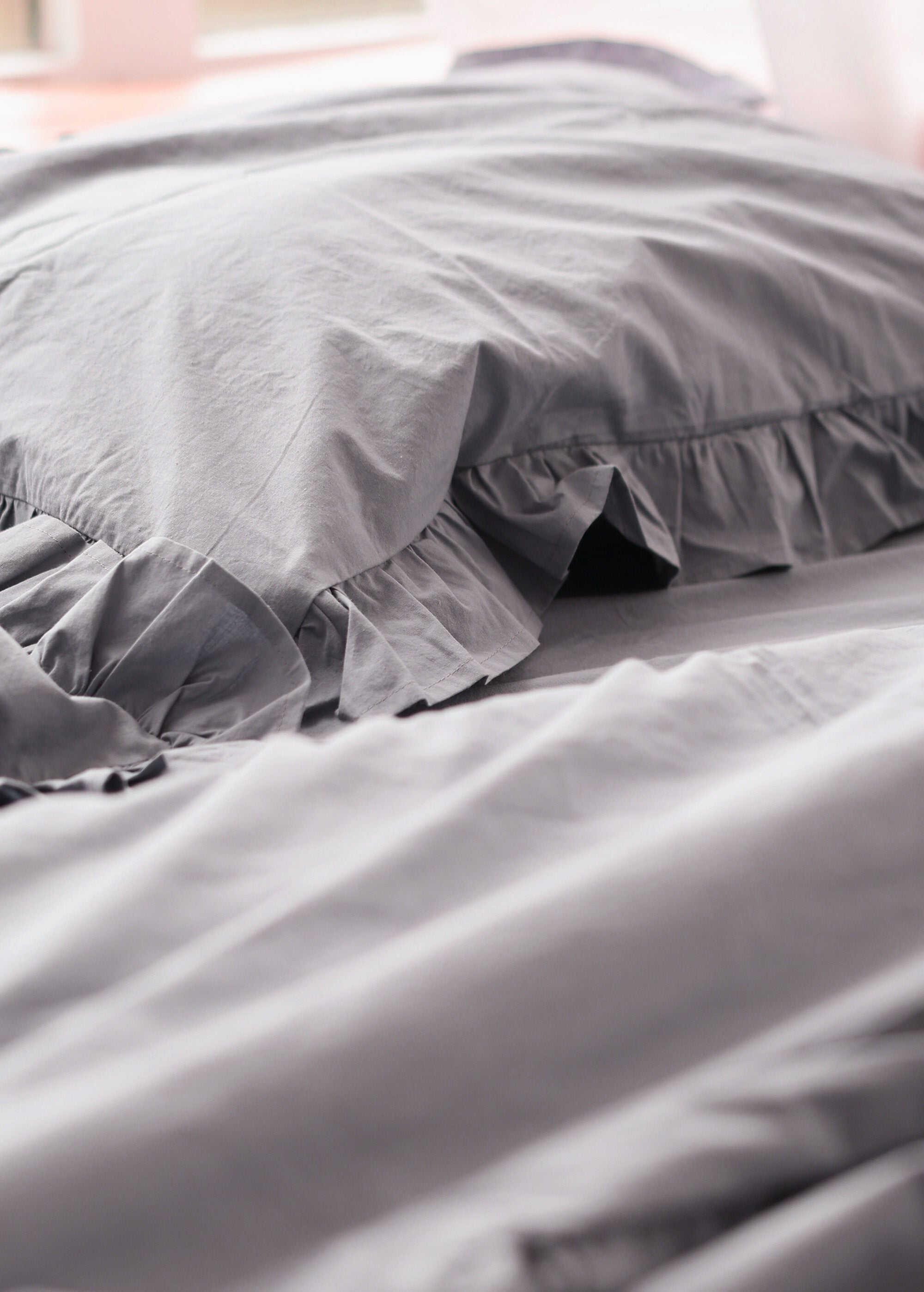 a black and white photo of a bed with a ruffled pillow