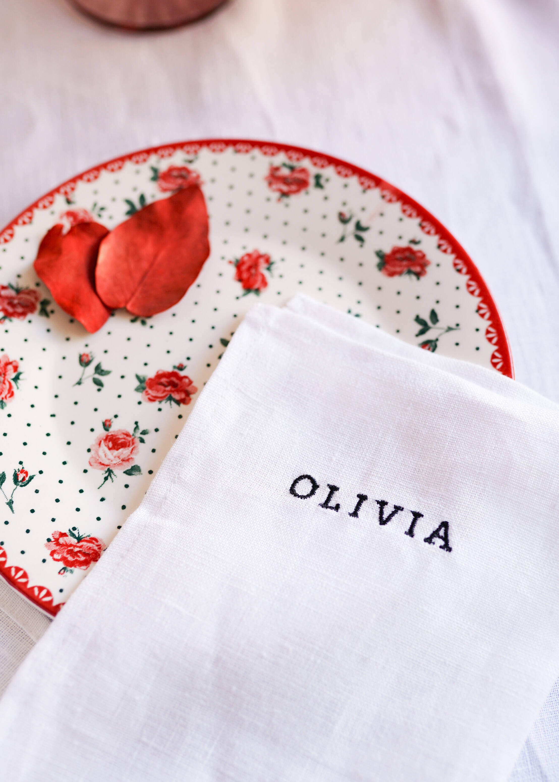 a white table cloth with a red rose on it