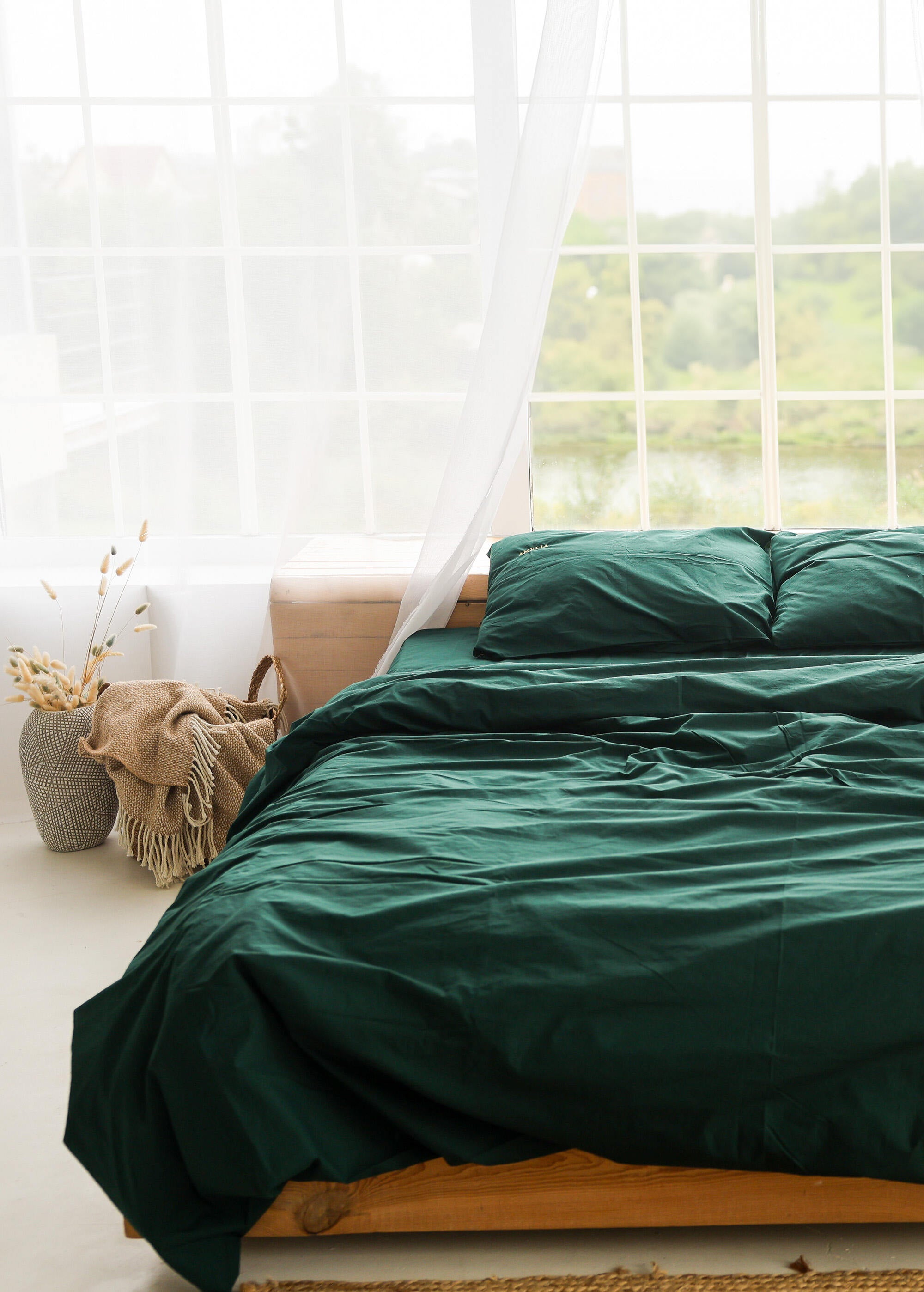 a bed with a green comforter and pillows