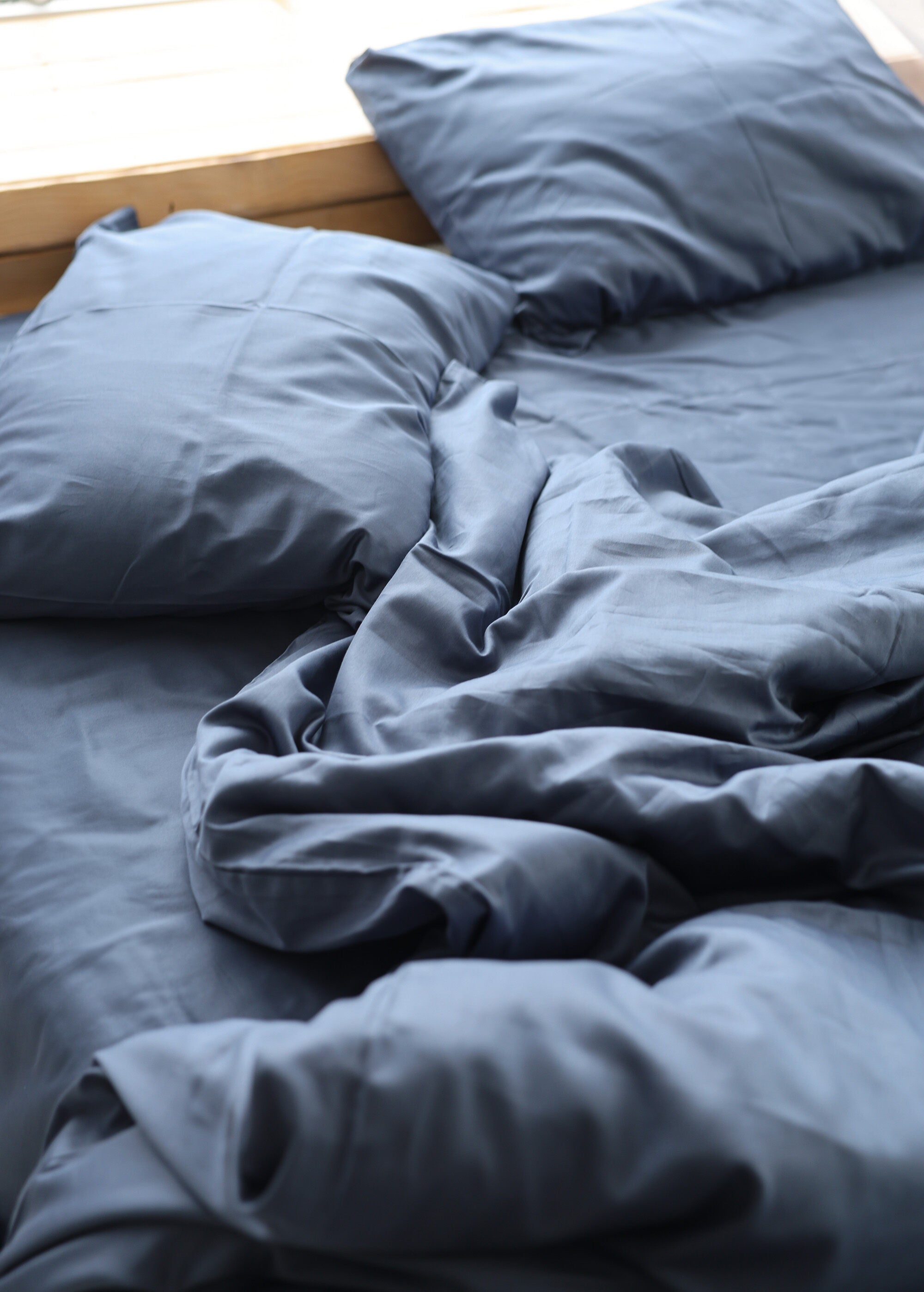 a bed with a blue comforter and pillows