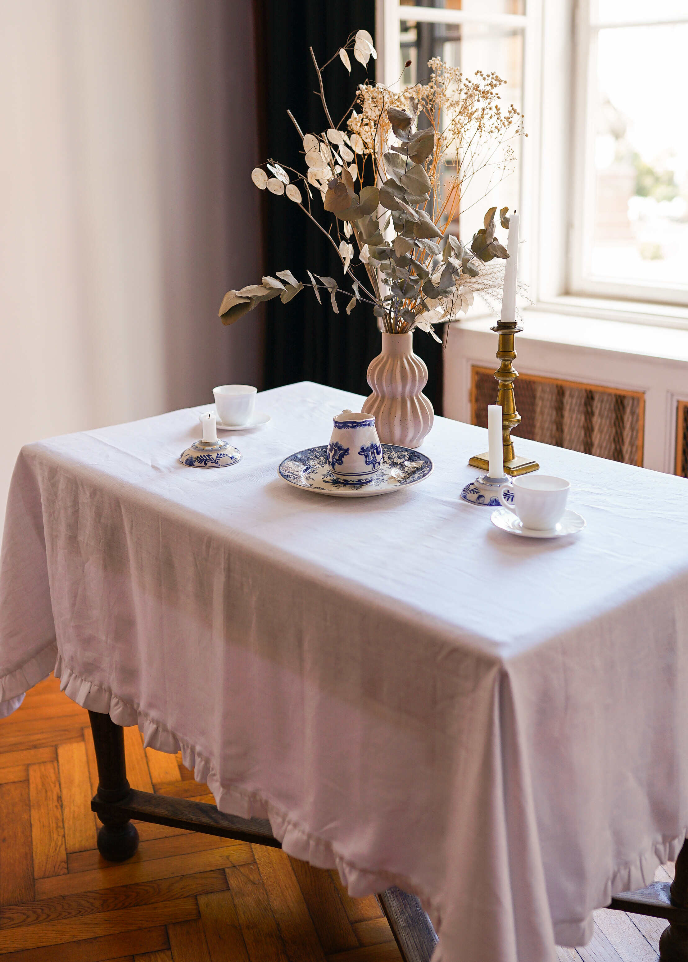 a table with a vase of flowers and tea cups on it