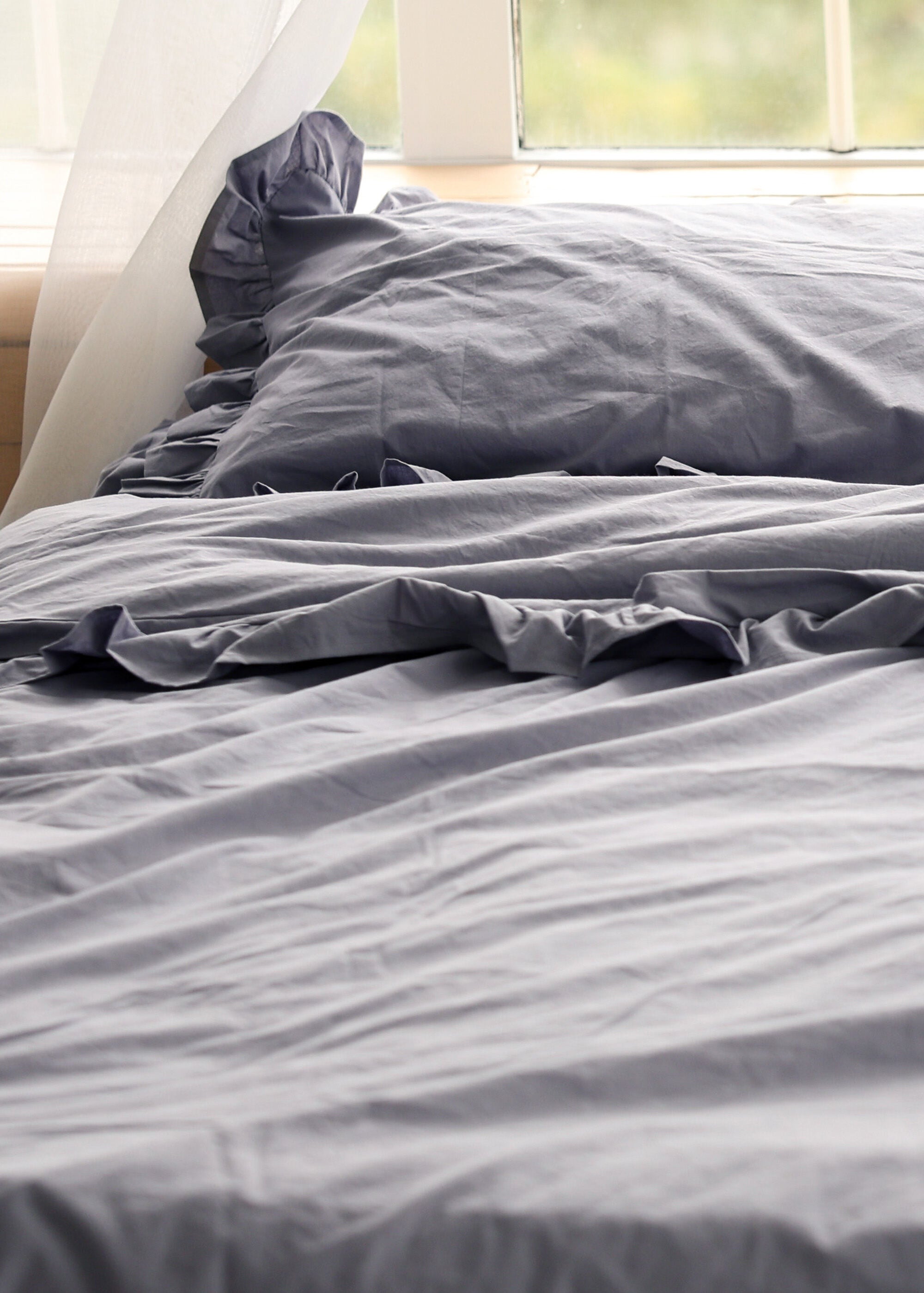 a bed with a blue comforter and a window