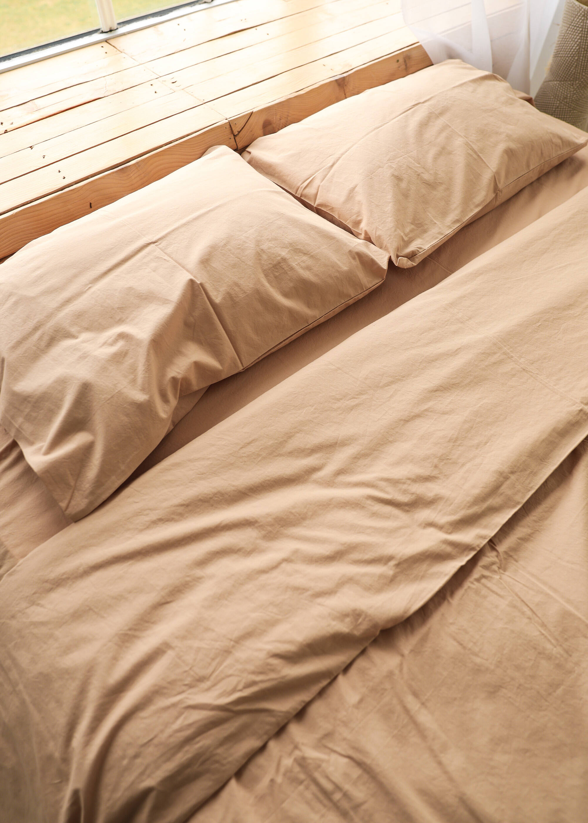 a bed with a tan comforter and two pillows