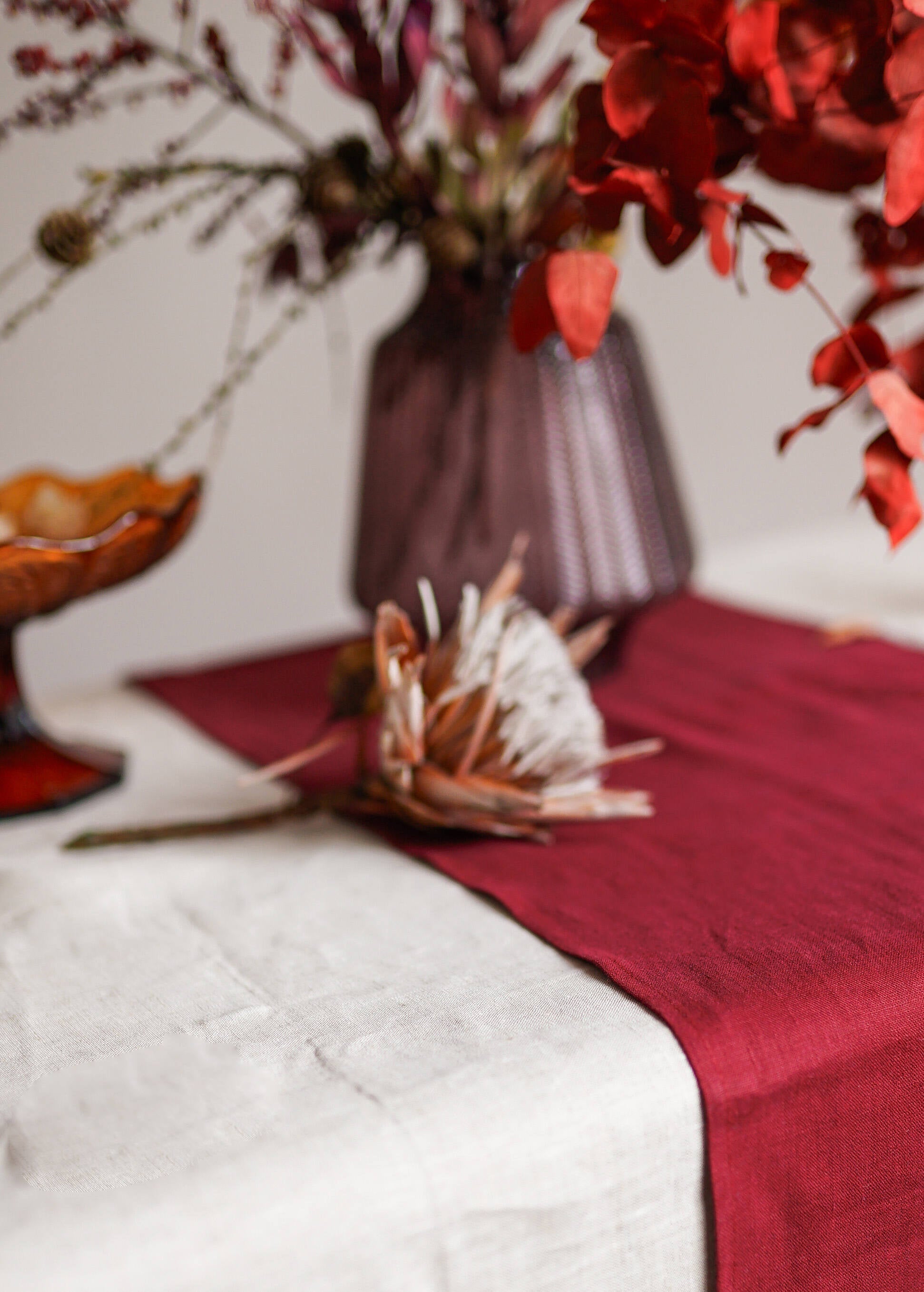 a table topped with a vase filled with red flowers