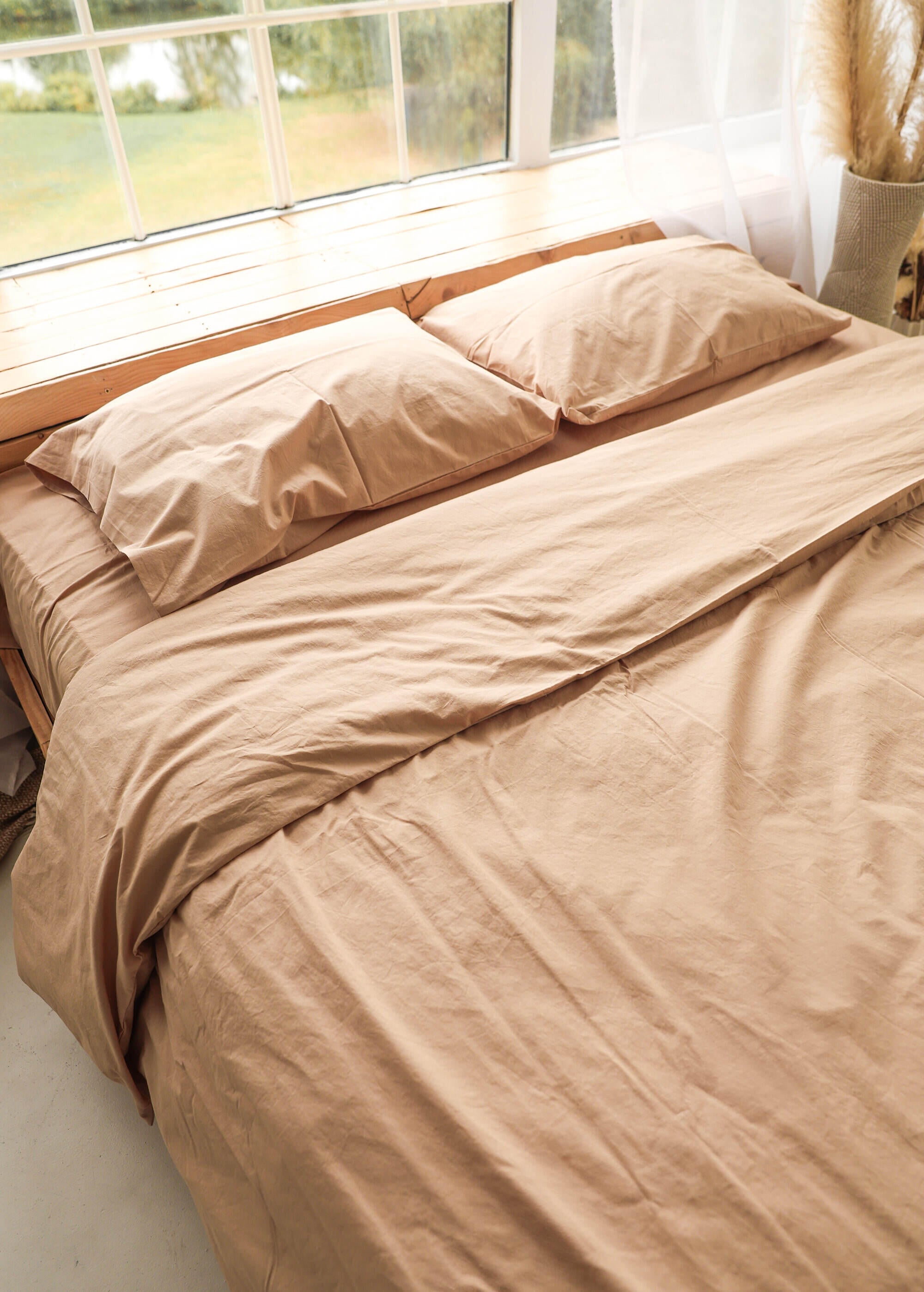 a bed with a tan comforter and pillows