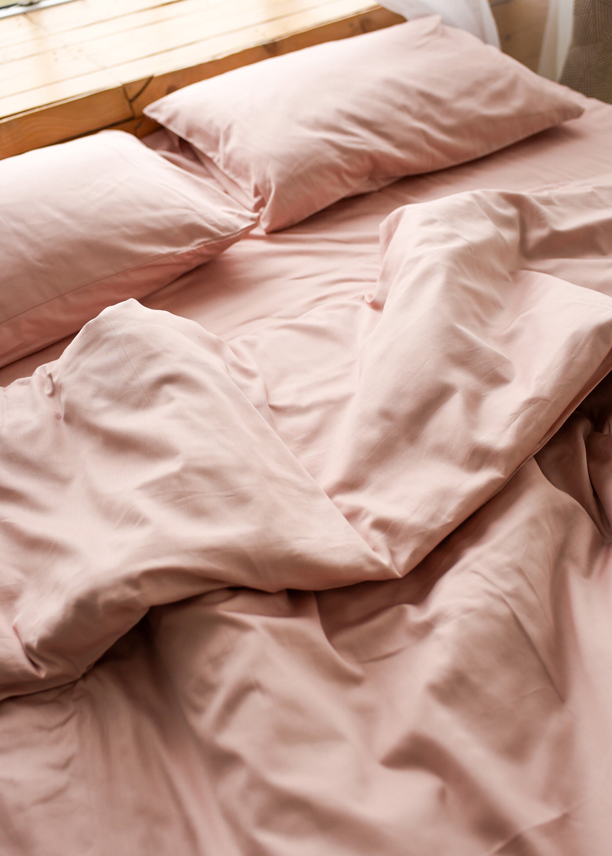 an unmade bed with pink sheets and pillows