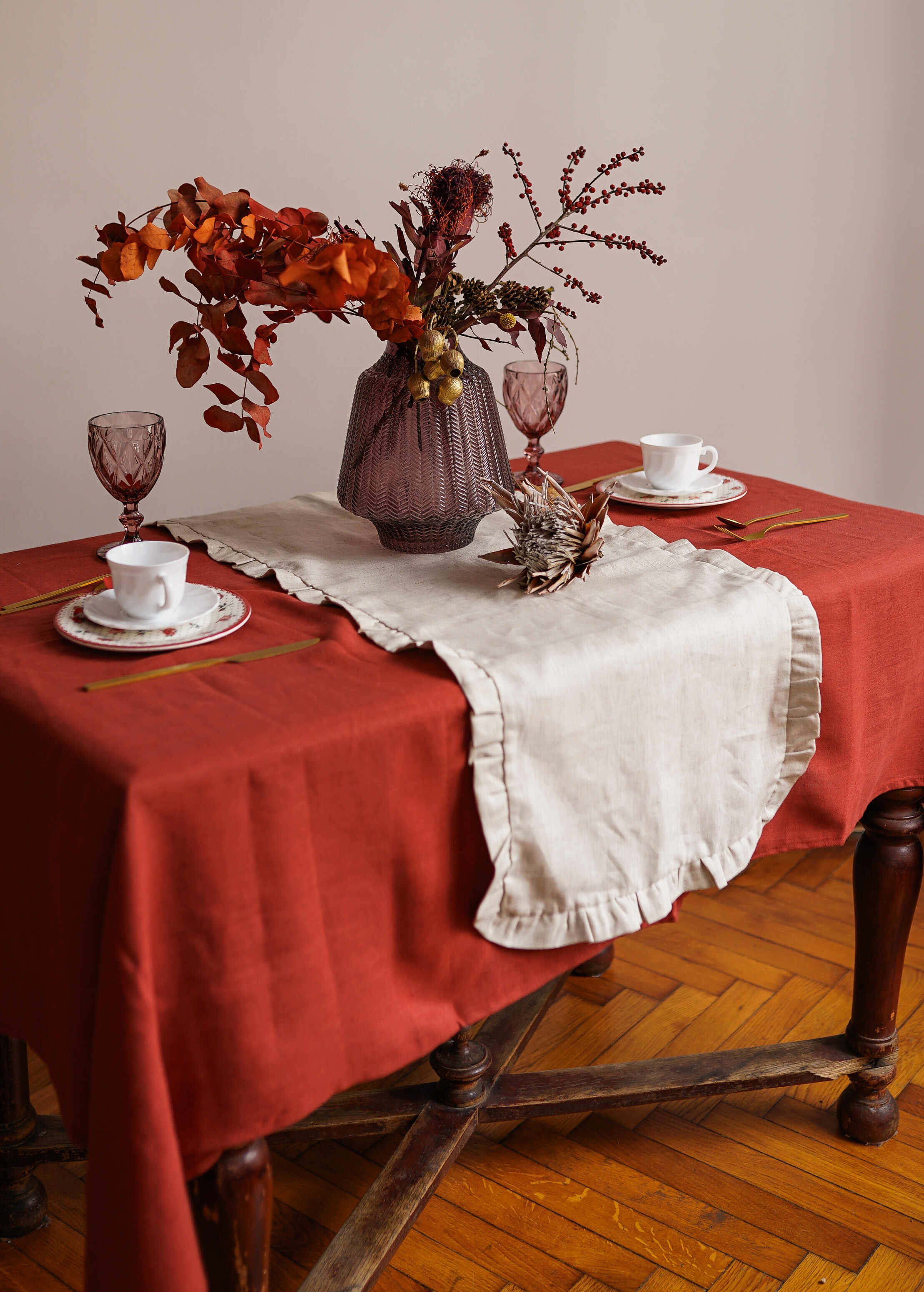 a table topped with a vase of flowers next to a cup and saucer