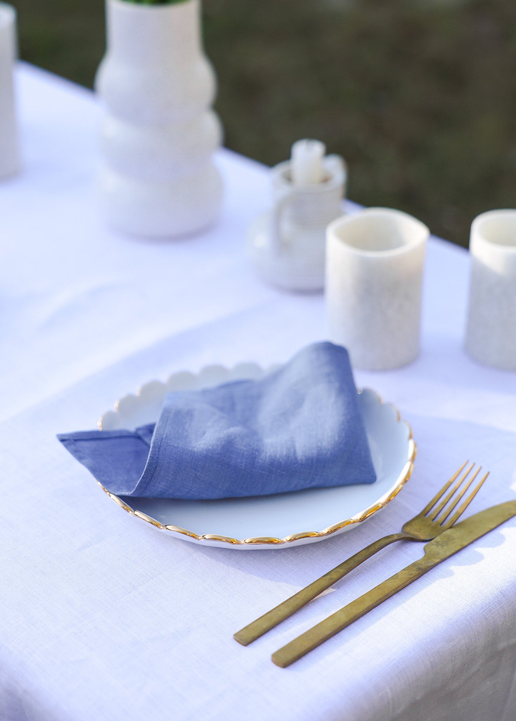 a white table with a blue napkin and gold fork