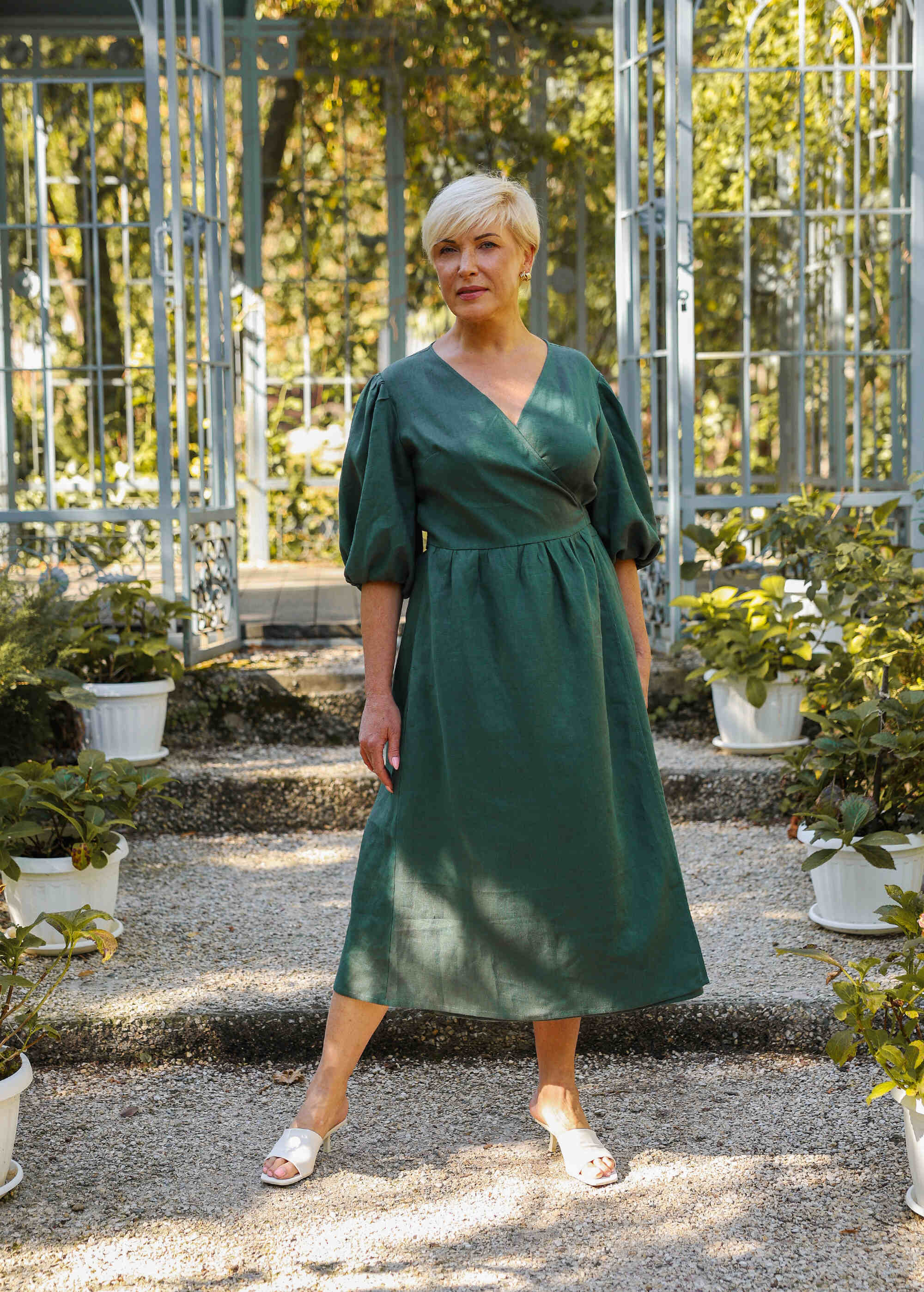 a woman in a green dress standing in a garden