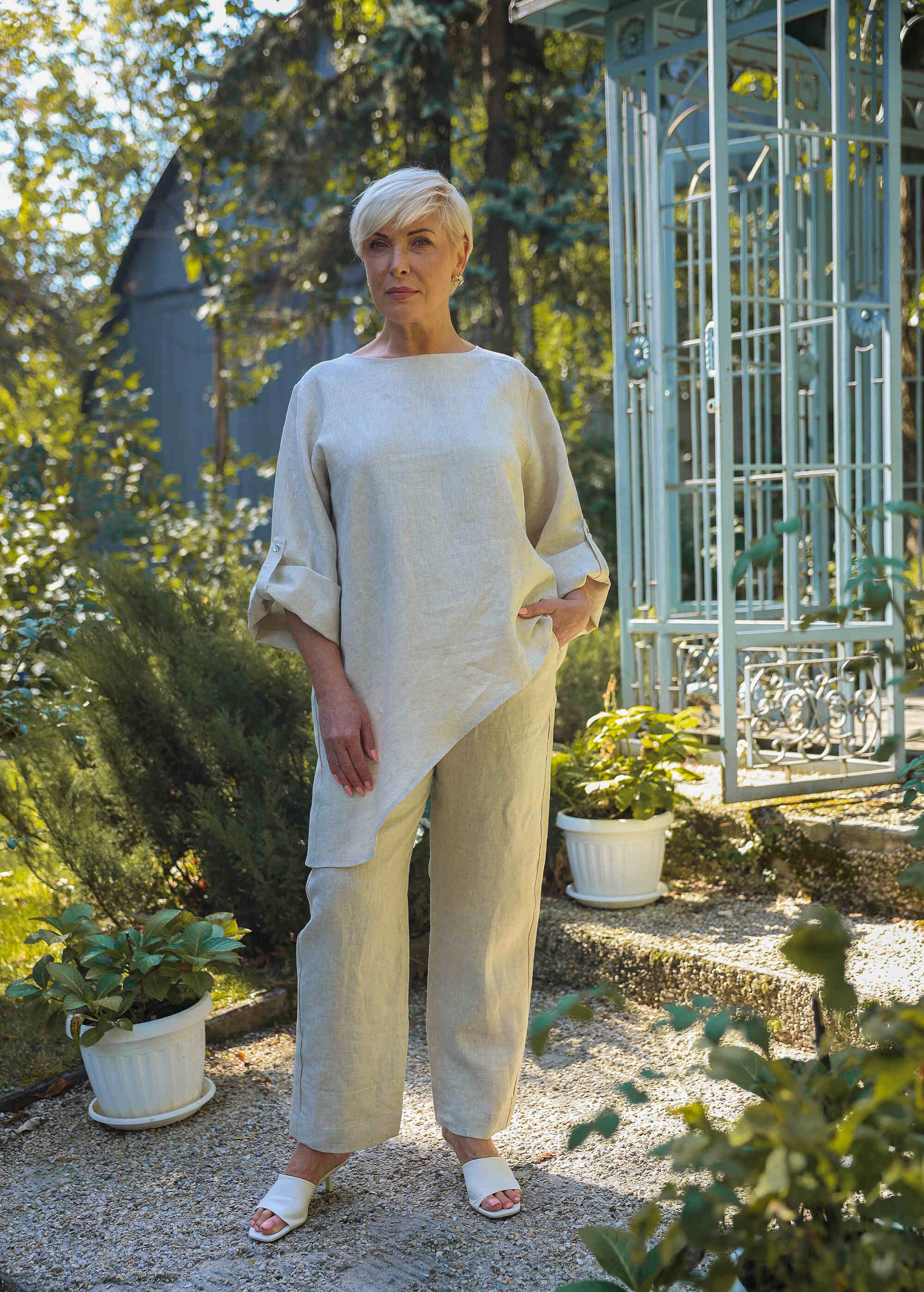 a woman standing in a garden with a gazebo in the background