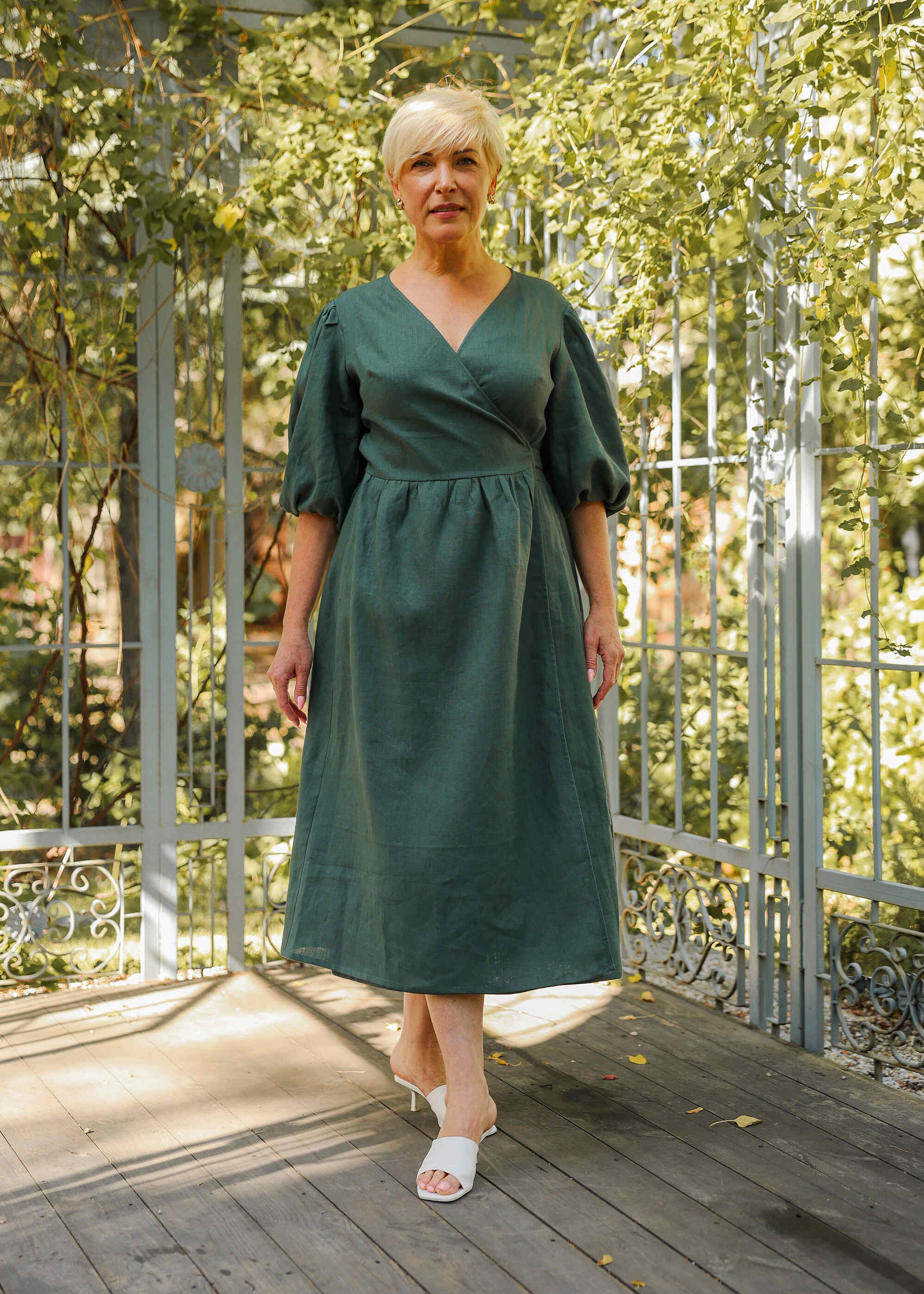 a woman in a green dress standing on a porch