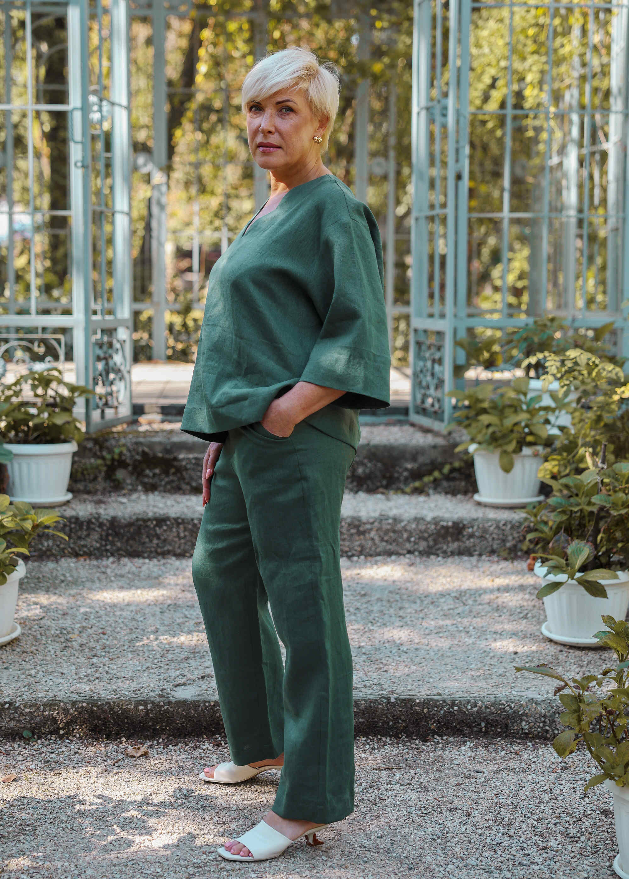 a woman standing in front of some potted plants