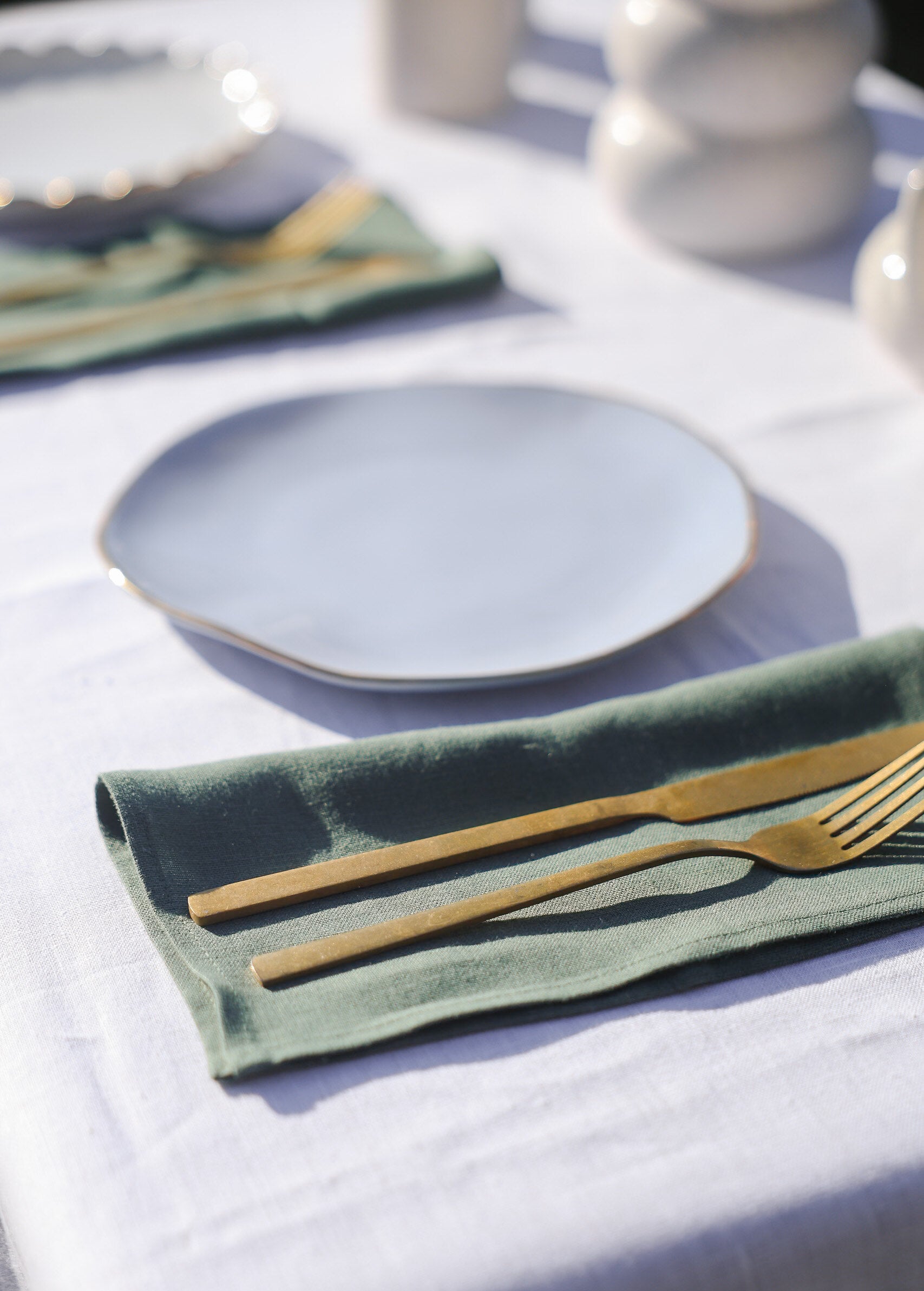 a table set with a white table cloth and gold cutlery