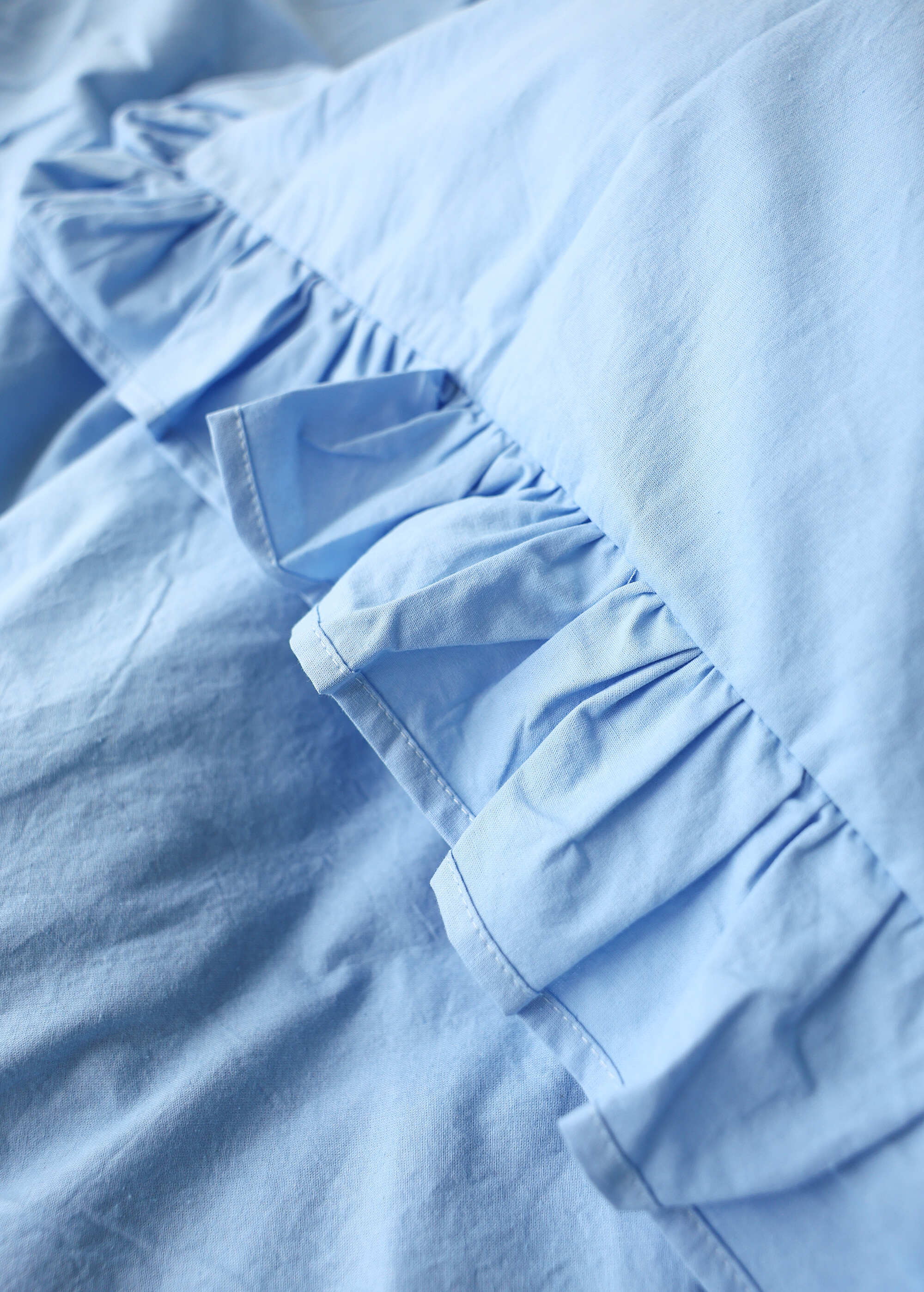 a close up of a blue shirt with ruffles