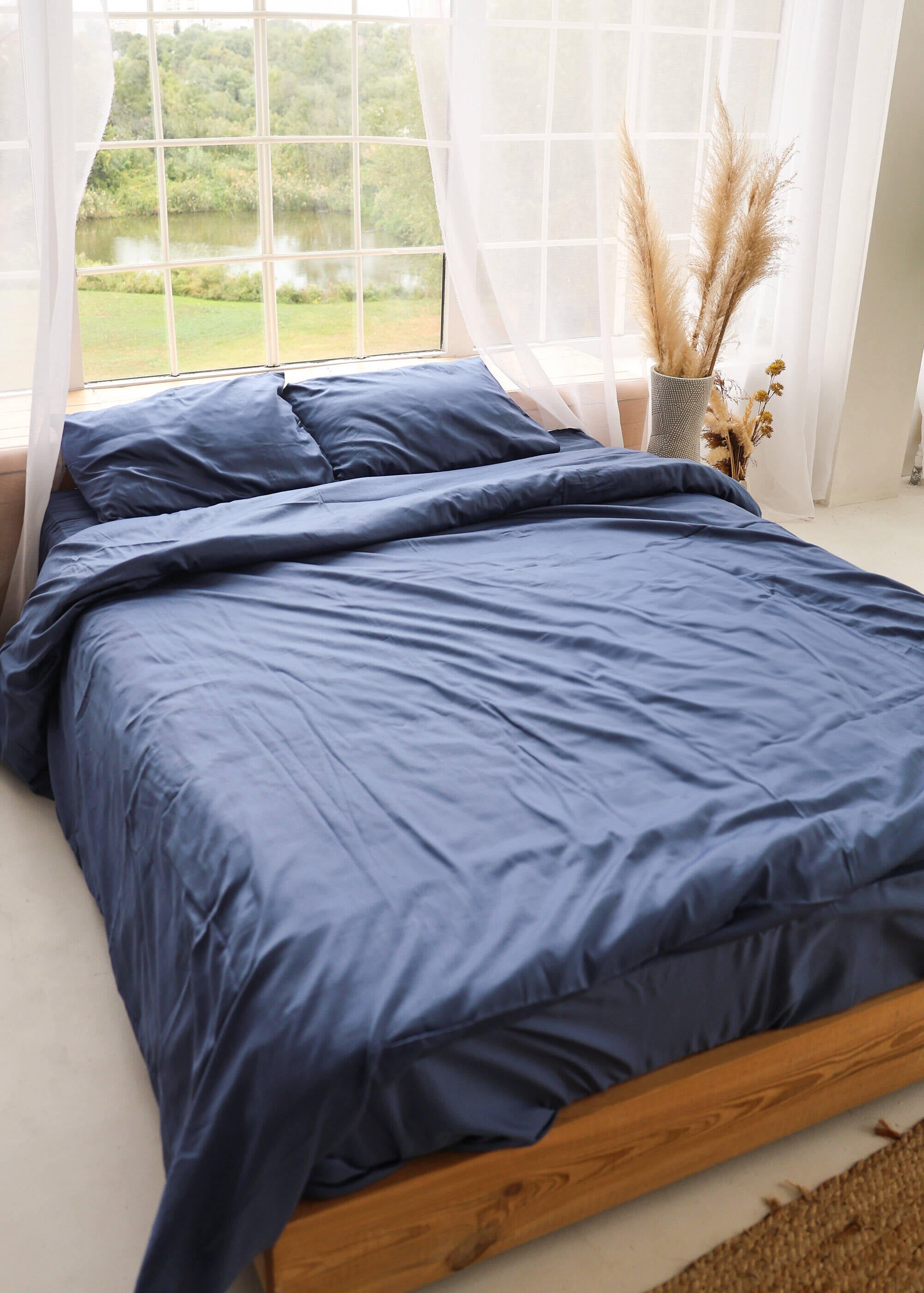 a bed with a blue comforter and pillows