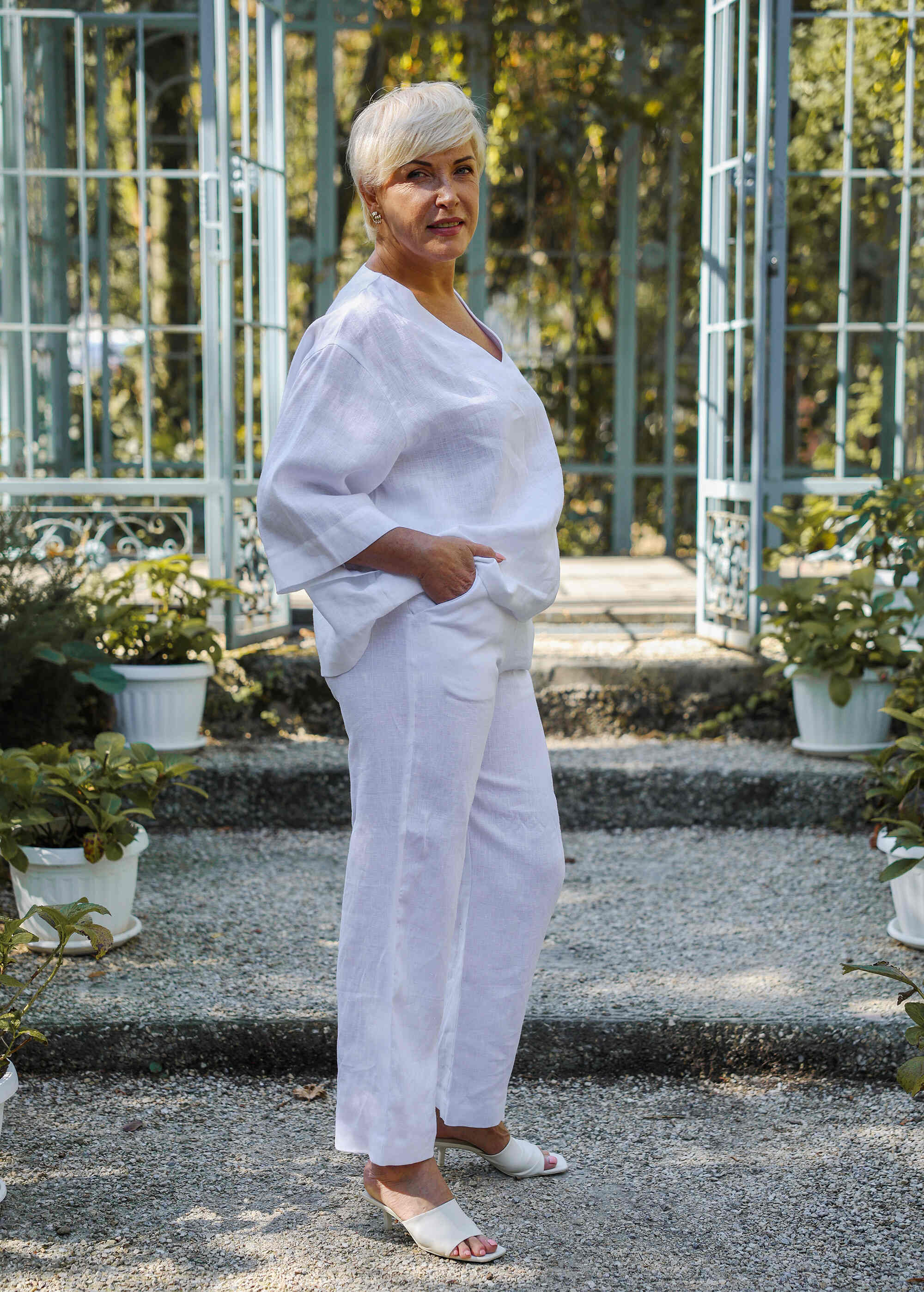 a woman in a white outfit standing in a garden