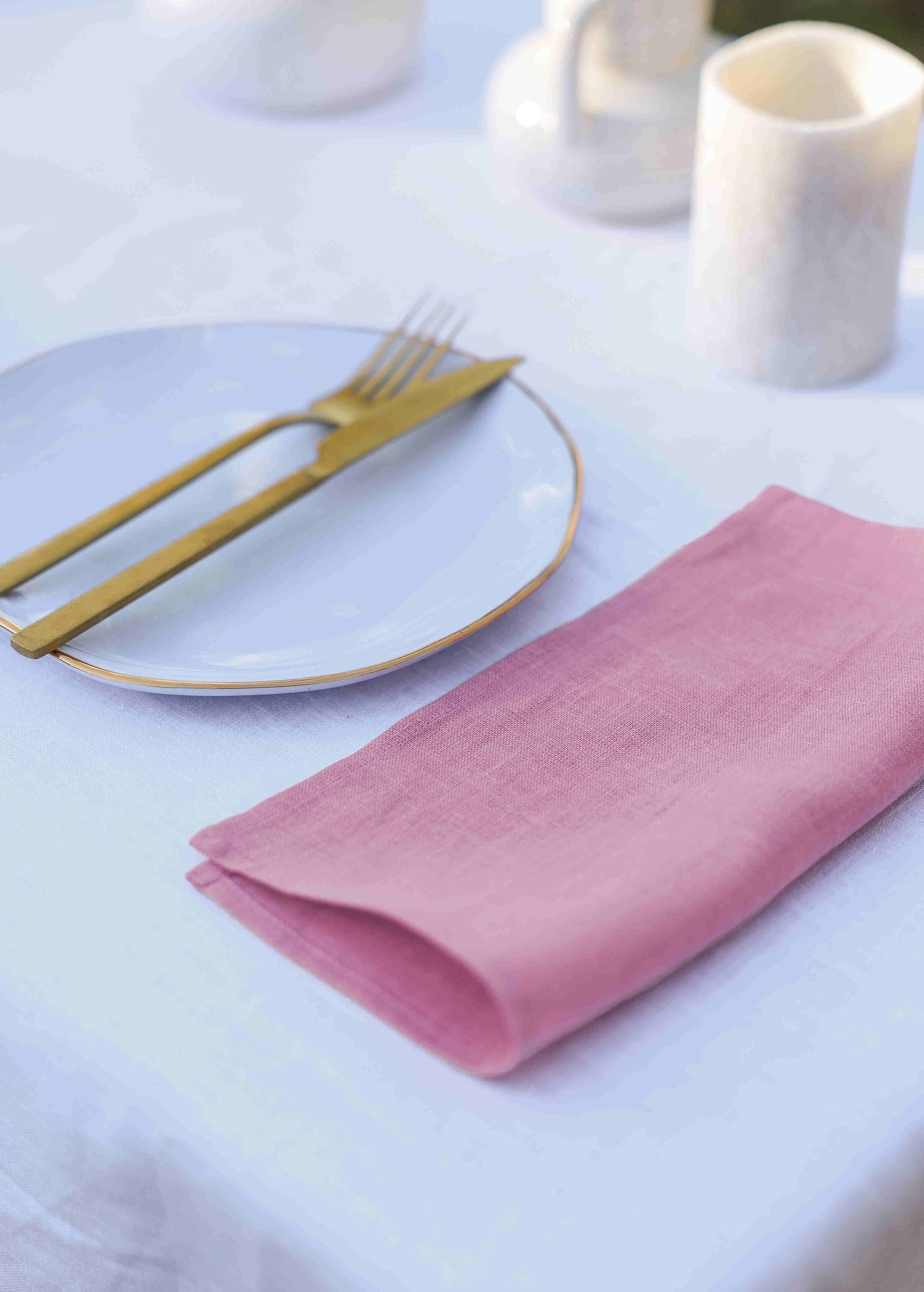 a place setting with a pink napkin and gold fork