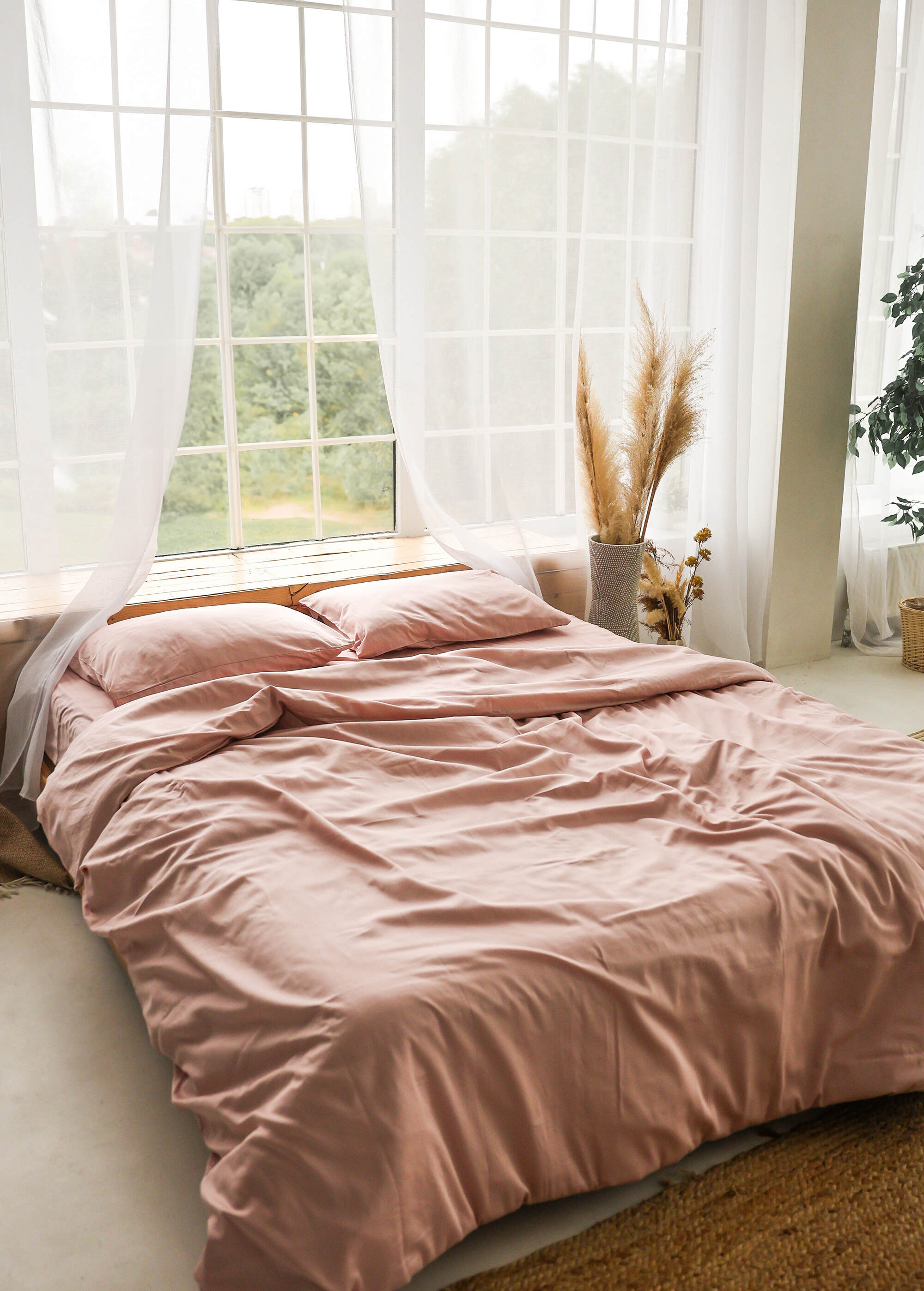 a bed with a pink comforter and pillows