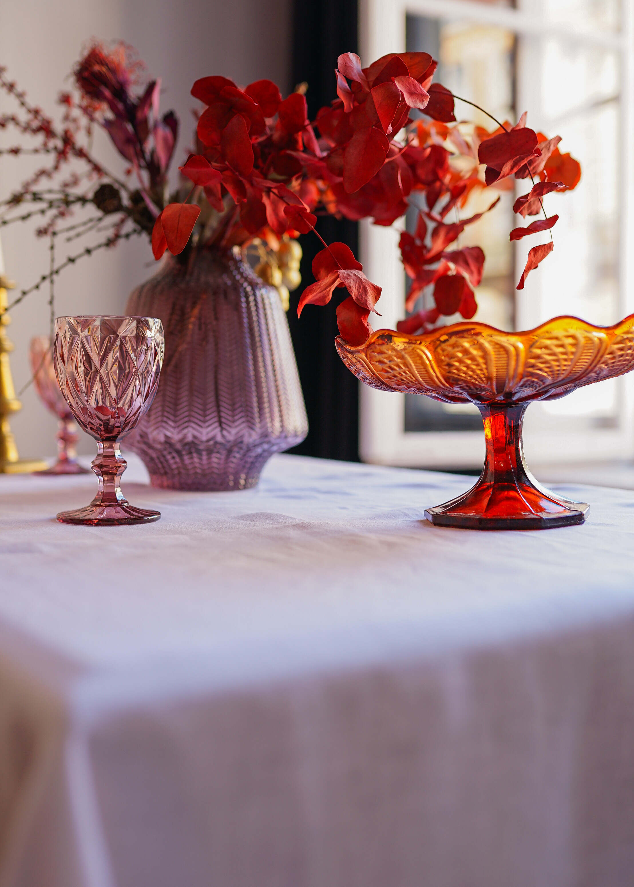 a table topped with vases filled with red flowers