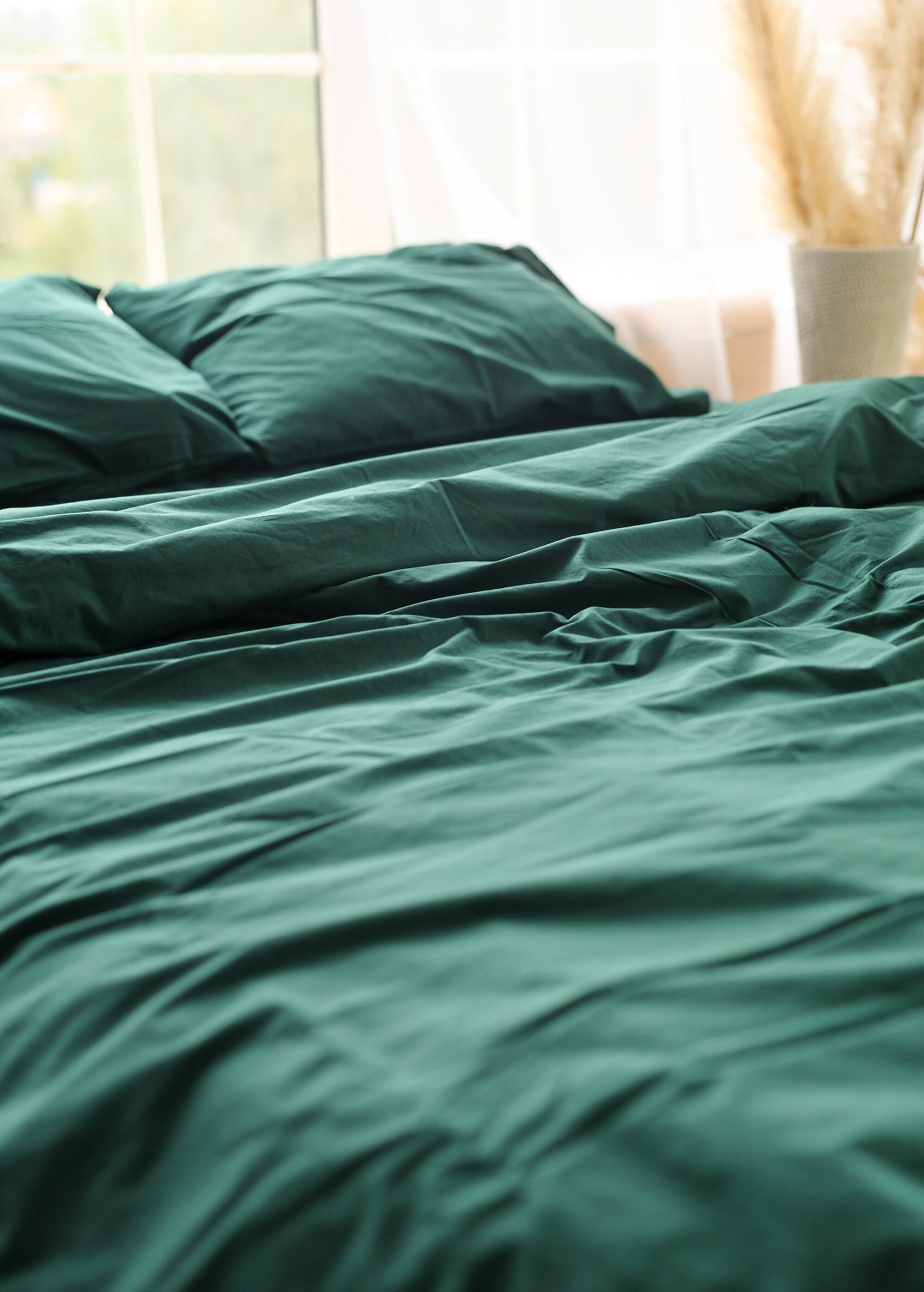 a bed with a green comforter and pillows