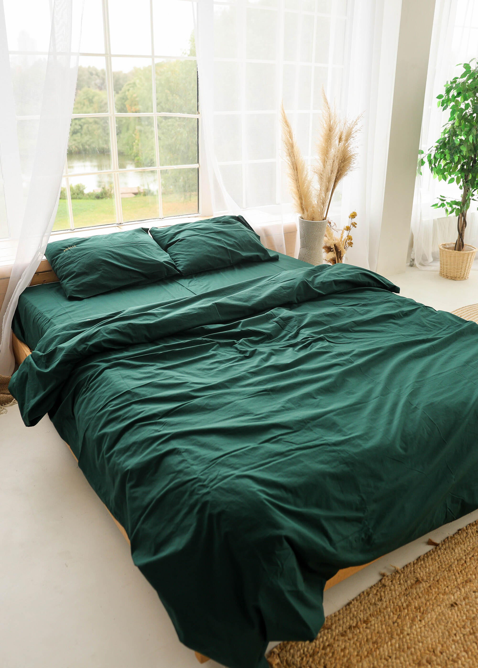 a bed with a green comforter and pillows